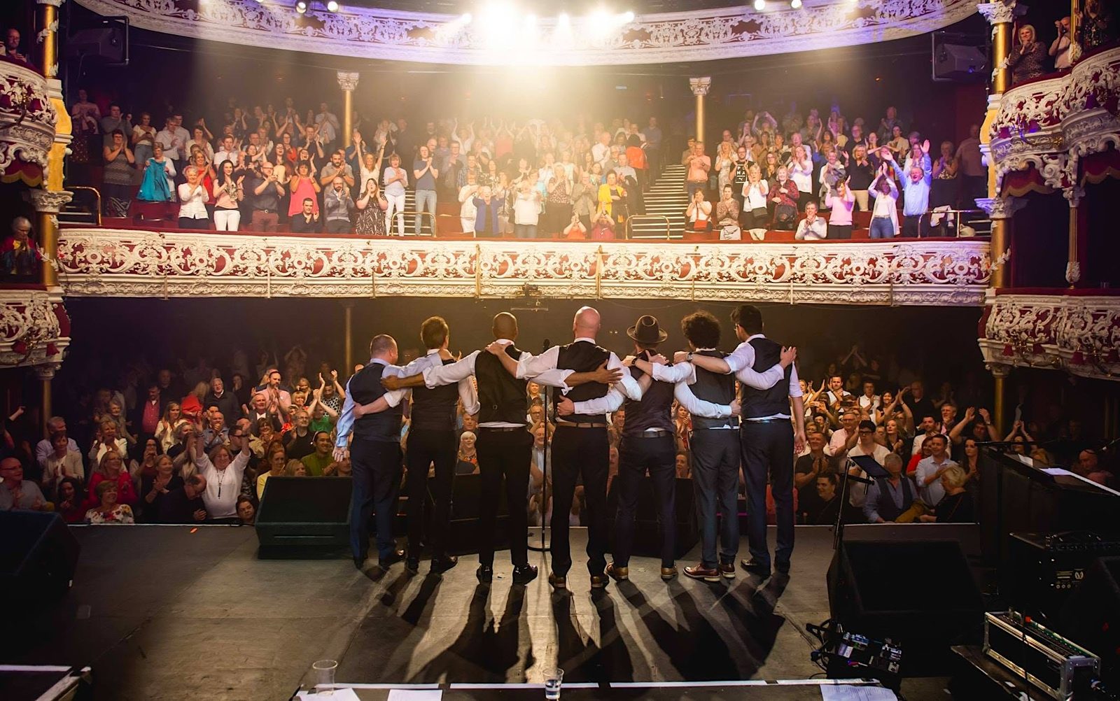 The band arm in arm taking a bow on stage at the Olympia Theatre, Dublin, as a packed house gives a standing ovation